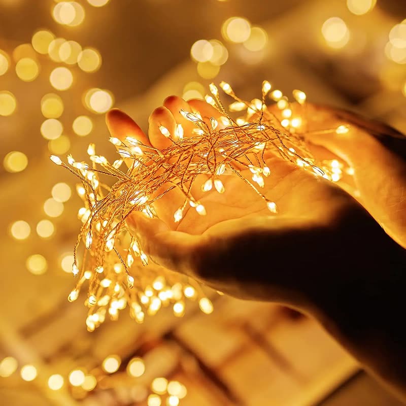 A hand holding a cluster of tiny warm firefly fairy lights against a background of soft glowing lights (seller photo from the AliExpress listing)
