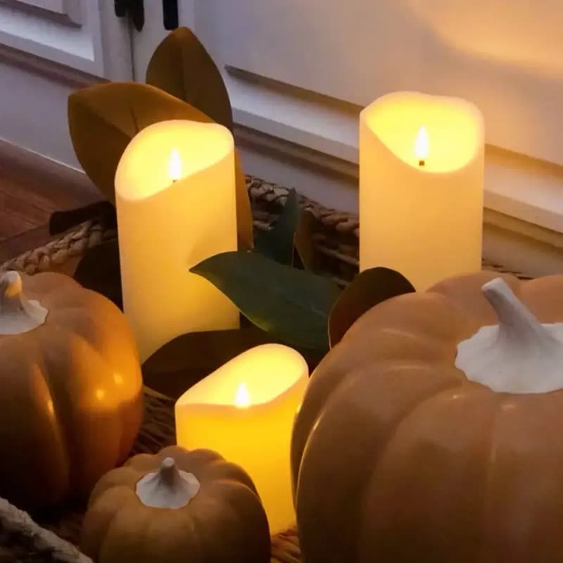 Flameless LED pillar candles of different heights glowing among orange and white pumpkins (seller photo from the AliExpress listing)