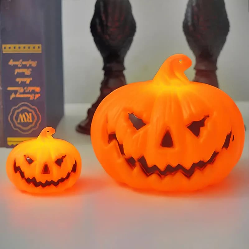 Two glowing orange jack-o'-lantern pumpkin lights, one small and one large, on a white table (seller photo from the AliExpress listing)