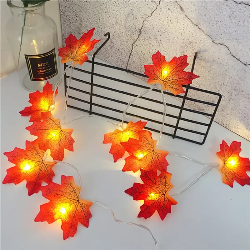 Red and orange maple leaf garland with warm fairy lights draped over a wire basket and a table (seller photo from the AliExpress listing)
