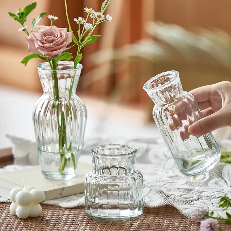 Clear ribbed glass bud vases of different heights on a table, some holding a single flower (seller photo from the AliExpress listing)